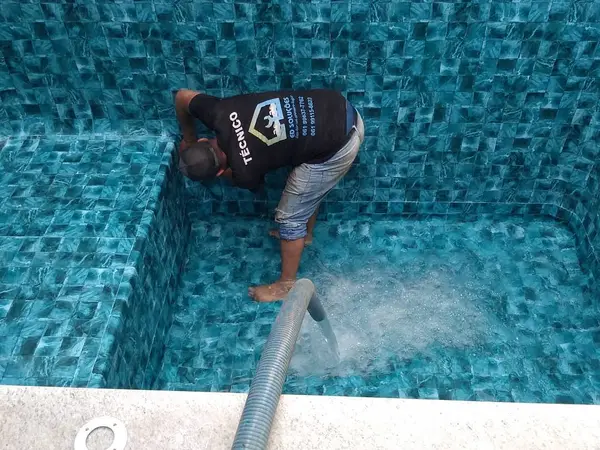 Técnico posicionando o mangote no fundo da piscina em São Luís - MA